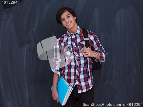 Image of arab teenager  with school backpack and books against black chal