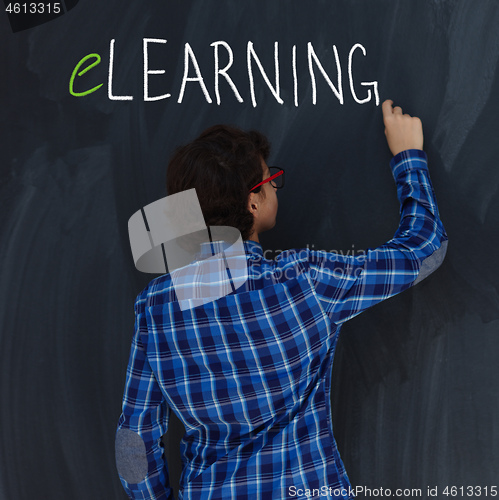 Image of Teen Boy with chalk  writing on black chalkboard elearning