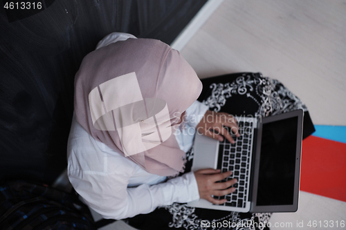 Image of arab female student working on laptop from home