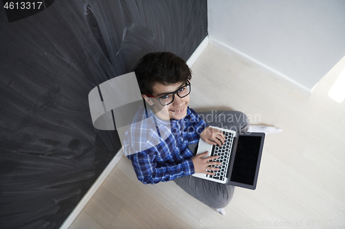 Image of Arab teenager using laptop to work on homework  at home