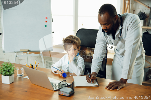 Image of Little caucasian boy as a doctor consulting for patient, working in cabinet, close up