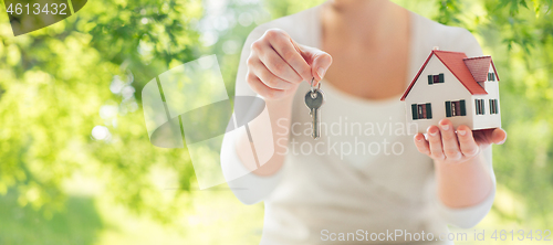 Image of close up of hands holding house model and keys