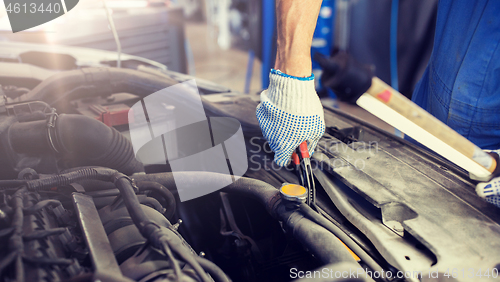 Image of mechanic man with pliers repairing car at workshop