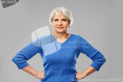 Image of senior woman in blue sweater hands on hips