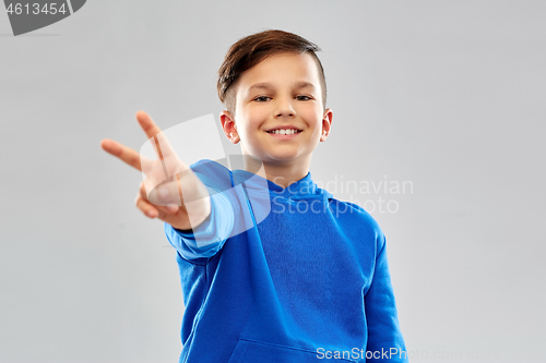 Image of smiling boy in blue hoodie showing peace gesture