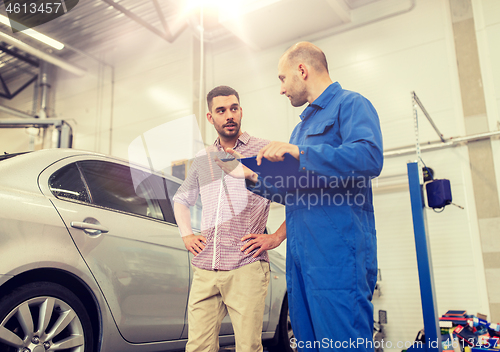 Image of auto mechanic with clipboard and man at car shop