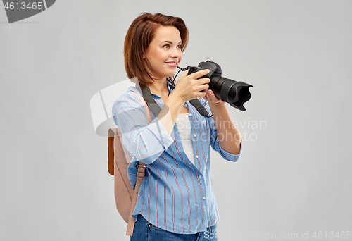 Image of happy tourist woman with backpack and camera