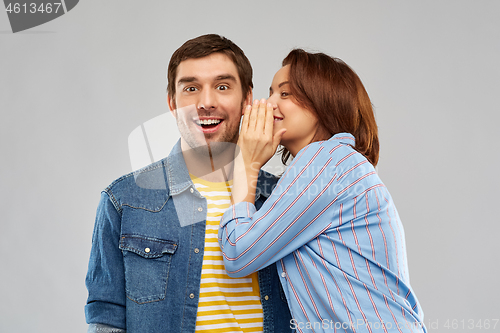 Image of happy couple whispering over grey background