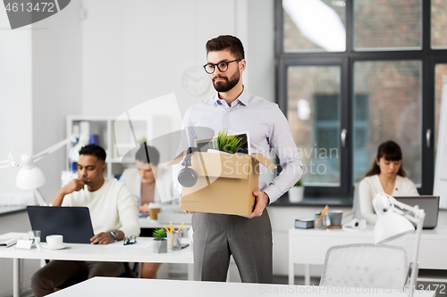 Image of sad fired male office worker with personal stuff