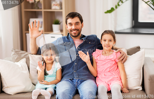 Image of happy father with daughters waving hands at home