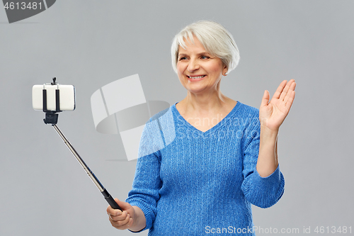 Image of smiling senior woman taking selfie by smartphone