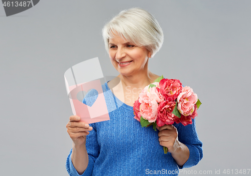 Image of happy senior woman with flowers and greeting card