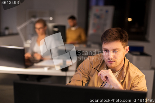 Image of man with computer working late at night office