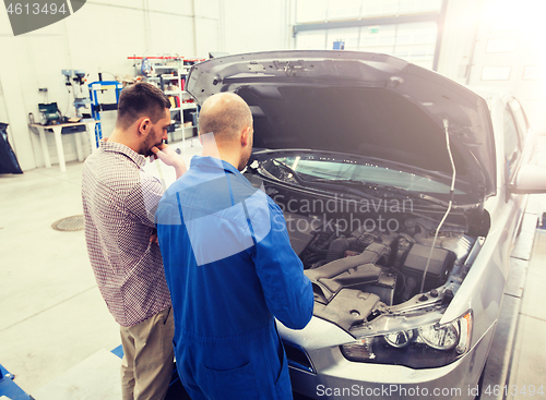 Image of auto mechanic and man or car owner at workshop