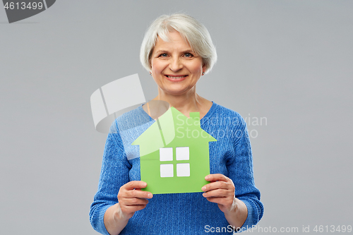 Image of smiling senior woman holding green house icon