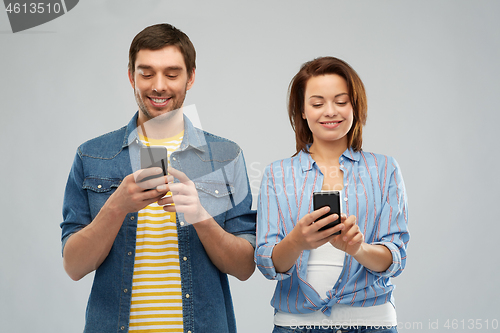 Image of happy couple using smartphones over grey