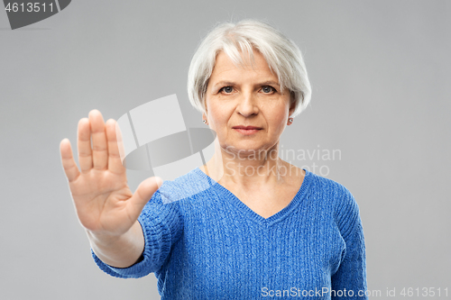 Image of senior woman in blue sweater making stop gesture