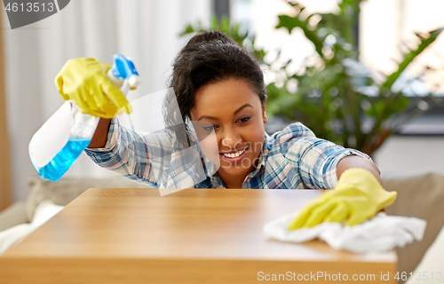 Image of african american woman cleaning table at home