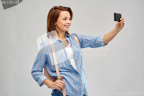 Image of woman with backpack taking selfie by smartphone