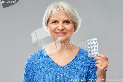 Image of smiling senior woman with pack of pills