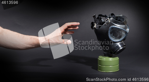 Image of Man in room, trying to reach for vintage gasmask - Green filter 