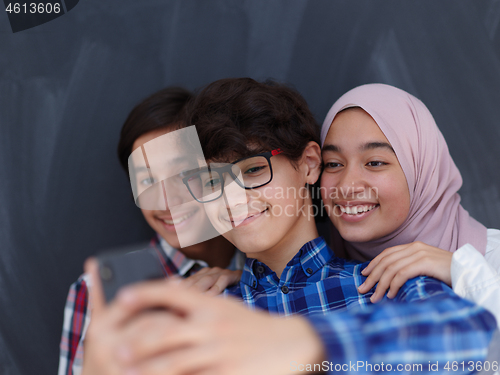 Image of group of arab teens taking selfie photo on smart phone