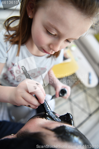 Image of mother and daughter at home making facial mask beauty treatment