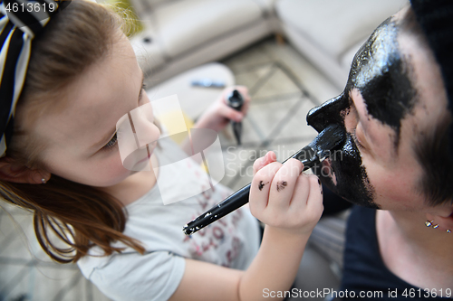 Image of mother and daughter at home making facial mask beauty treatment