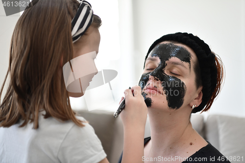 Image of mother and daughter at home making facial mask beauty treatment