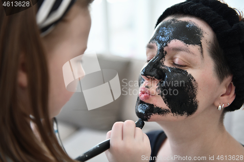 Image of mother and daughter at home making facial mask beauty treatment