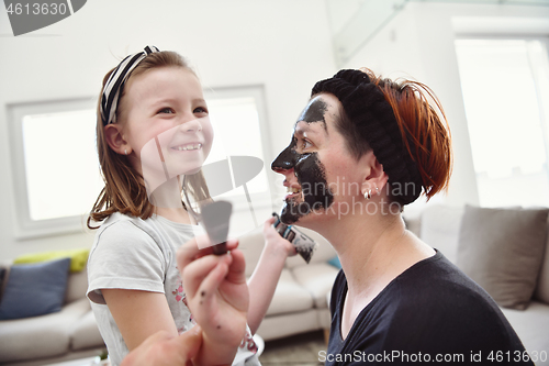 Image of mother and daughter at home making facial mask beauty treatment