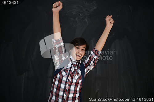 Image of happy arab teenager  celebrating against black chalkboard