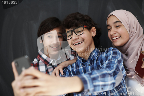 Image of group of arab teens taking selfie photo on smart phone