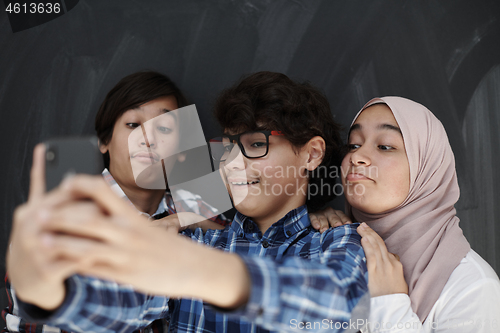 Image of group of arab teens taking selfie photo on smart phone