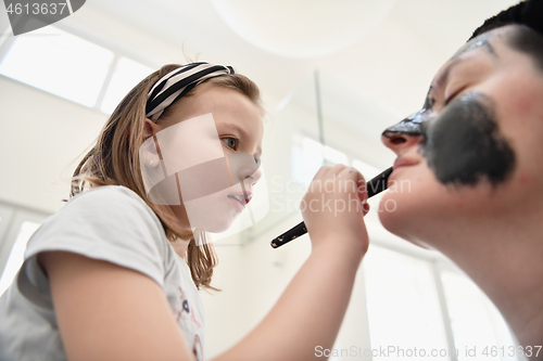 Image of mother and daughter at home making facial mask beauty treatment