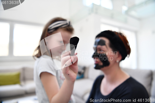 Image of mother and daughter at home making facial mask beauty treatment