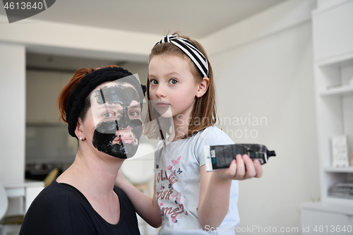 Image of mother and daughter at home making facial mask beauty treatment