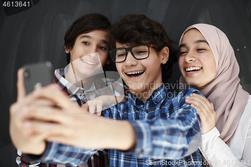 Image of group of arab teens taking selfie photo on smart phone