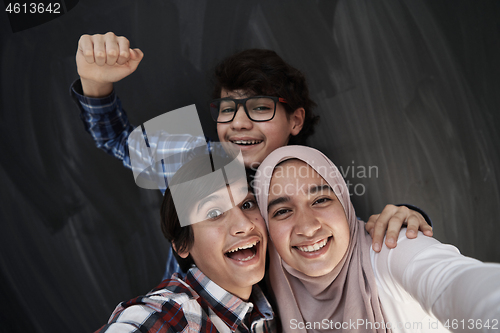 Image of group of arab teens taking selfie photo on smart phone