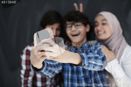 Image of group of arab teens taking selfie photo on smart phone