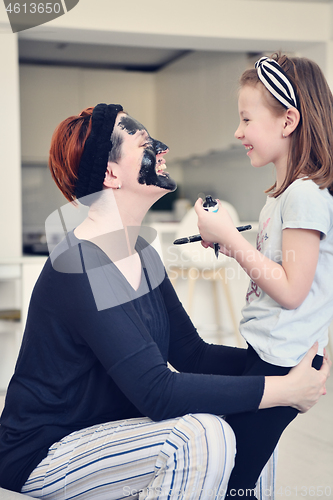 Image of mother and daughter at home making facial mask beauty treatment