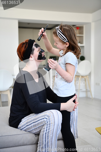 Image of mother and daughter at home making facial mask beauty treatment