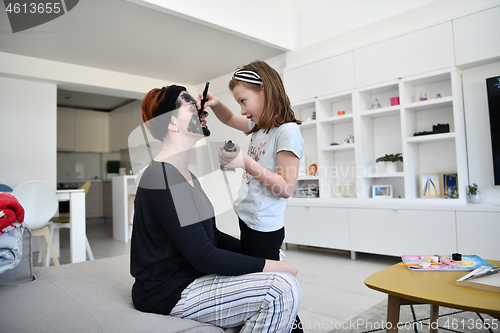 Image of mother and daughter at home making facial mask beauty treatment