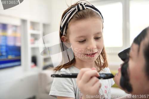 Image of mother and daughter at home making facial mask beauty treatment