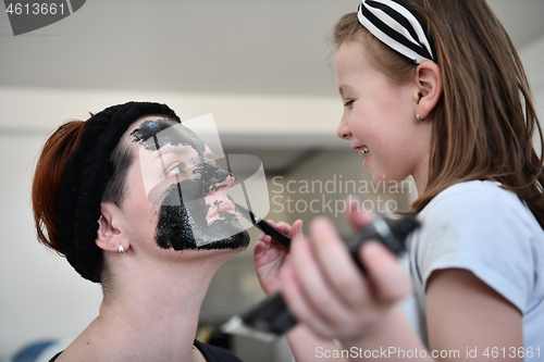 Image of mother and daughter at home making facial mask beauty treatment