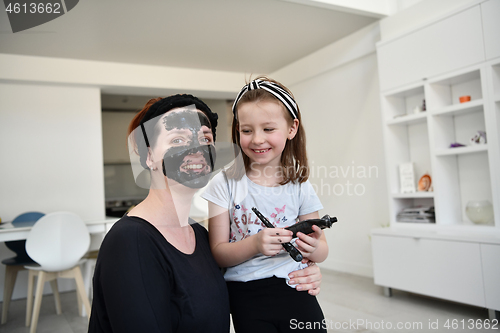 Image of mother and daughter at home making facial mask beauty treatment