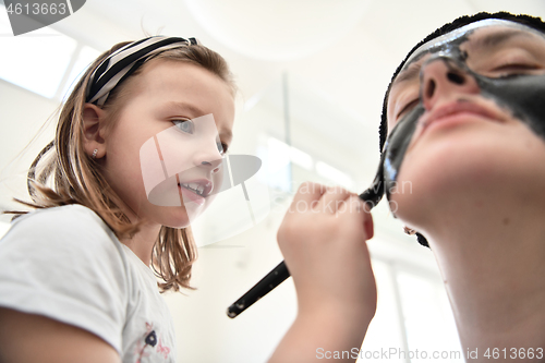 Image of mother and daughter at home making facial mask beauty treatment