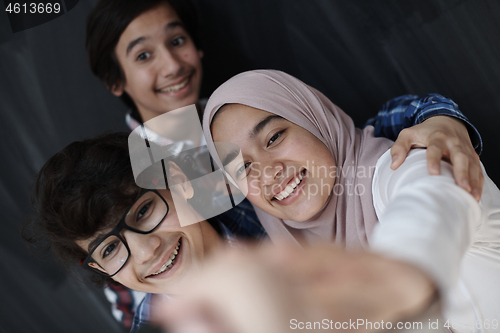 Image of group of arab teens taking selfie photo on smart phone