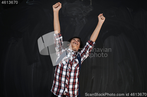 Image of happy arab teenager  celebrating against black chalkboard