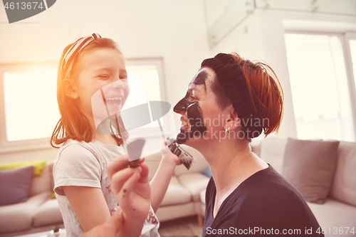 Image of mother and daughter at home making facial mask beauty treatment